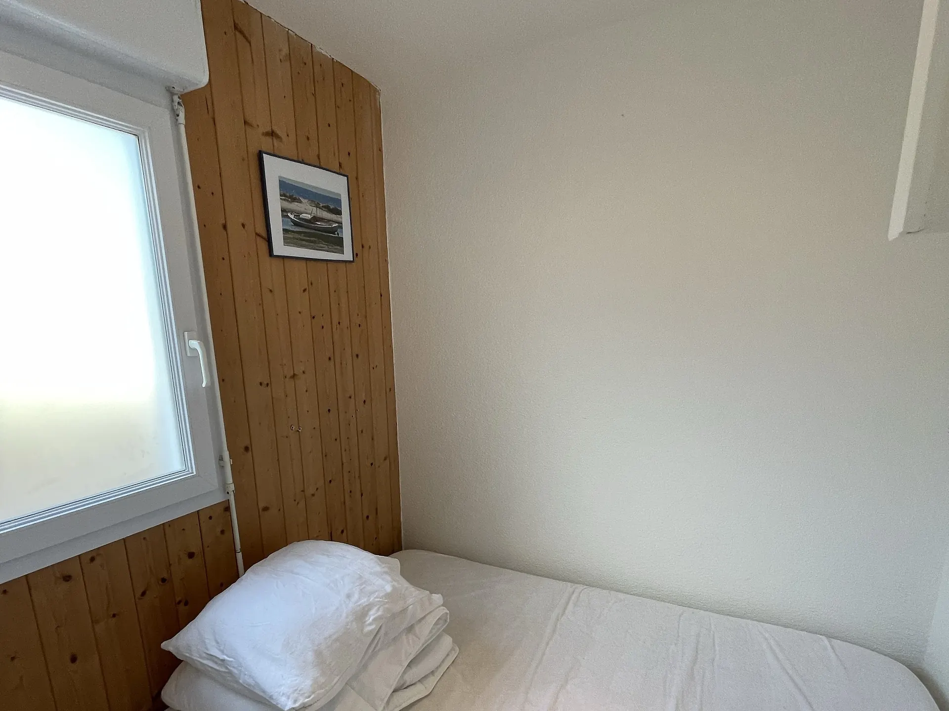 Small bedroom with a single bed beneath its boat print; bed linen is provided