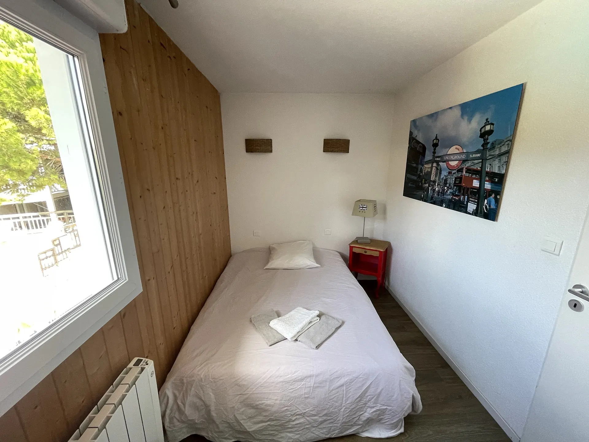 Bedroom with a single bed, red bedside table and wicker wall lights