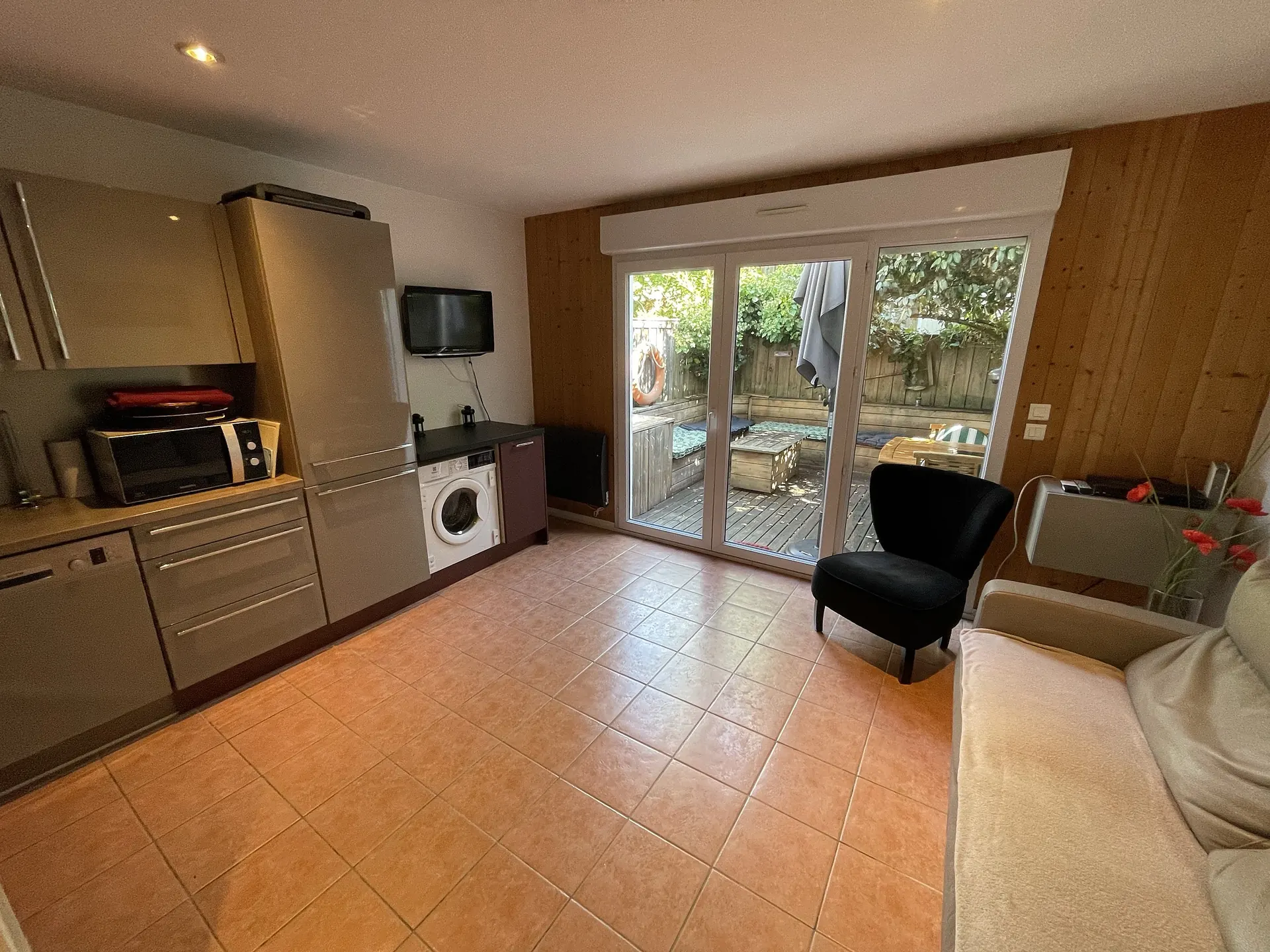 The kitchen open to the living room, with the glass door onto the terrace