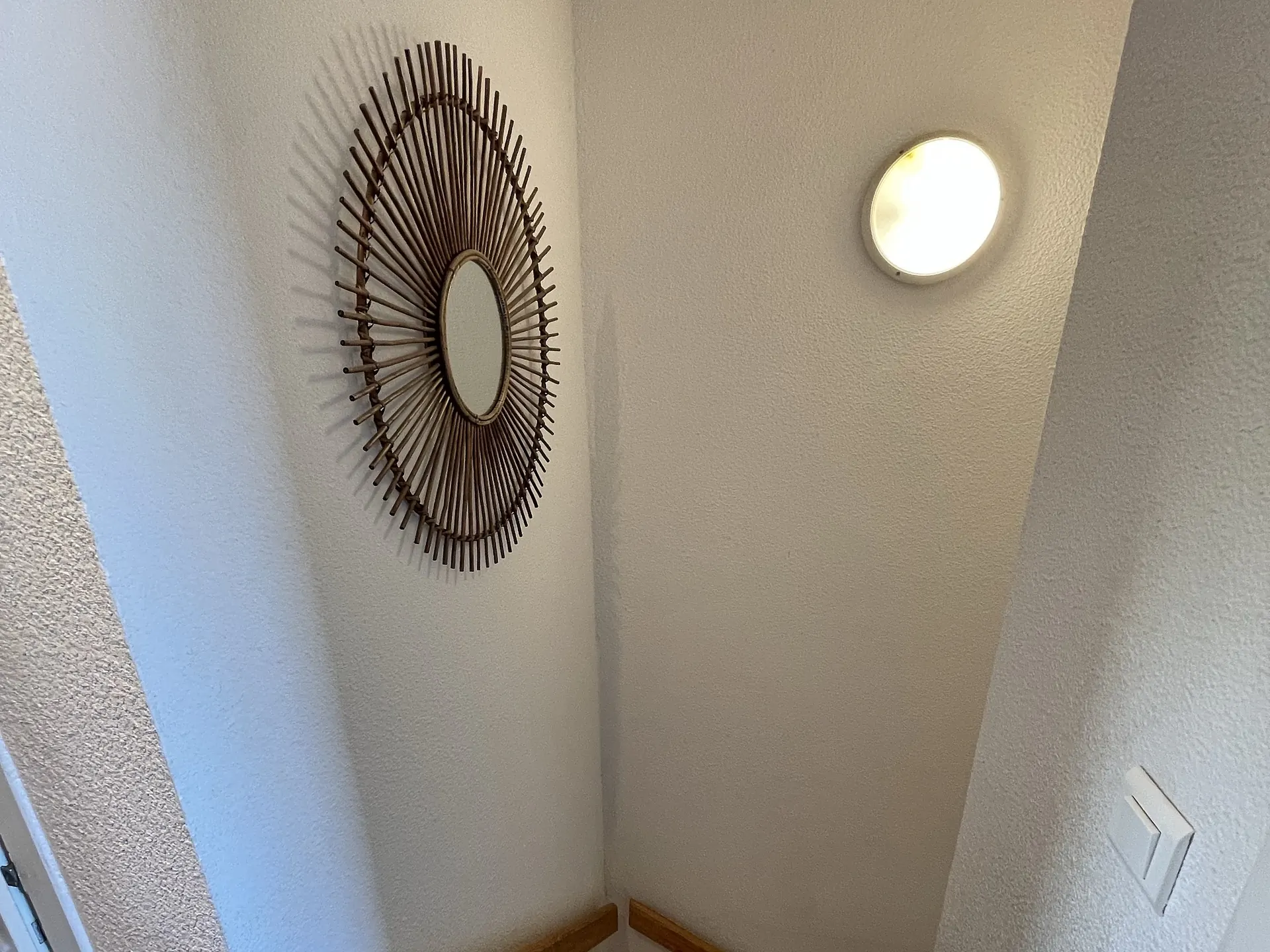 The wooden staircase up to the first floor, beneath its rattan mirror