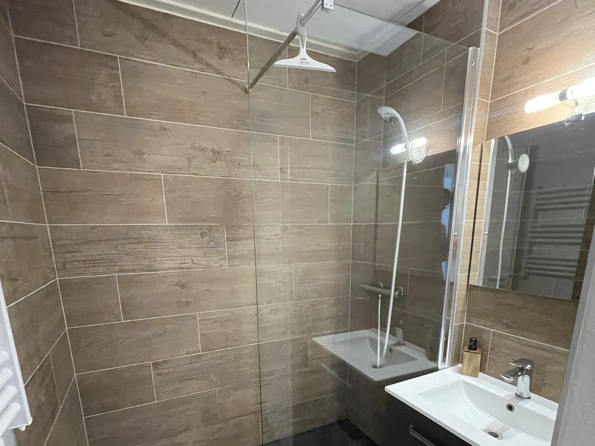 The bathroom, wood-effect tiling, walk-in shower with a built-in bench and vanity unit