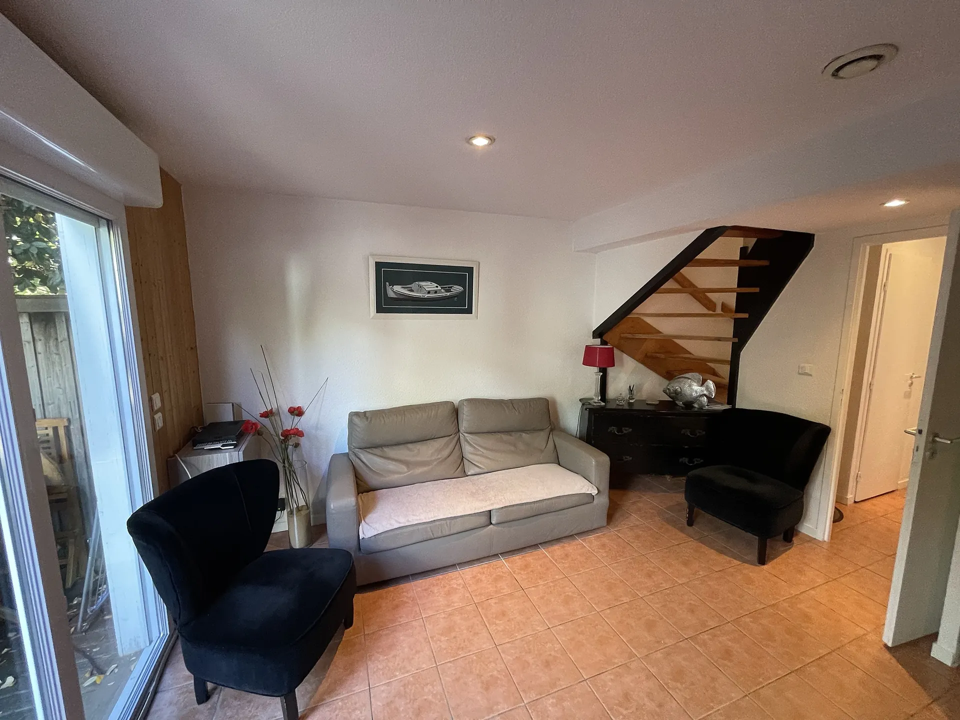 The living room: leather sofa, armchairs and the wooden staircase up to the first floor